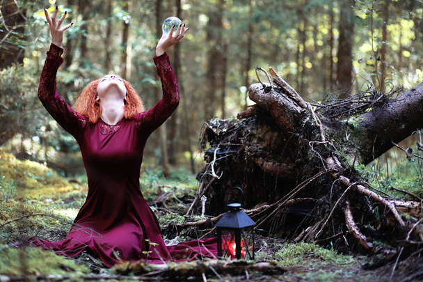 La bruja pelirroja sostiene un ritual con una bola de cristal
 - Foto, imagen