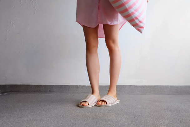 Girl Standing in Sleepwear and Pink Checkered Slippers with Holding Pink Pillow on Floor - Foto, immagini