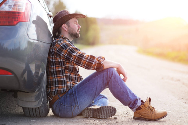 Man is sitting on the road by the car - Photo, Image