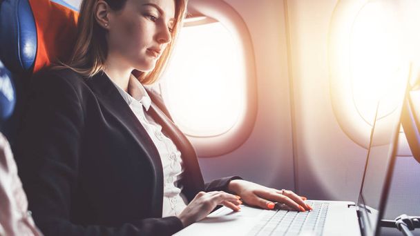 Женщина, работающая на ноутбуке во время путешествия на самолете
 - Фото, изображение