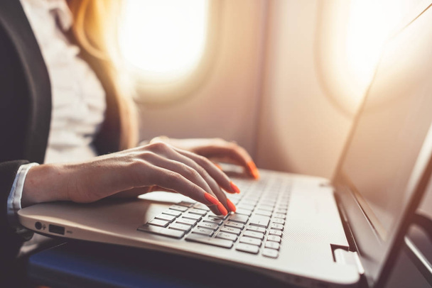 Close-up of female hands using laptop. Woman working while going on business trip by plane - Foto, immagini