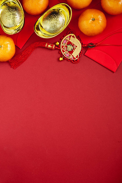 Şans ya da Çin düğüm ve Çin altın İngotlar ve geleneksel Çin düğüm (nimet yabancı metin anlamına gelir) ve kırmızı zarf ve dekorasyon kırmızı Kağıt arka plan üzerinde taze portakal ile Çin paraları - Fotoğraf, Görsel