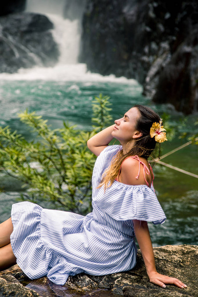 Menina sentada perto da cachoeira
 - Foto, Imagem