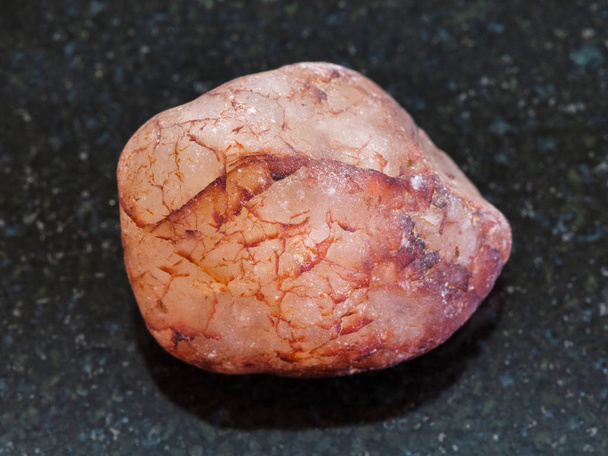 камешек из розового кварцевого камня на темном фоне
 - Фото, изображение