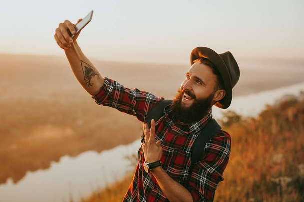 Smiling hipster taking selfie on nature - Foto, afbeelding