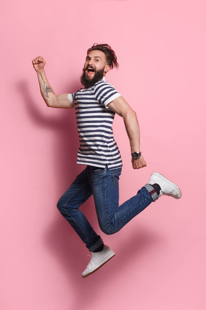 Excited man posing in jump on pink - Foto, afbeelding