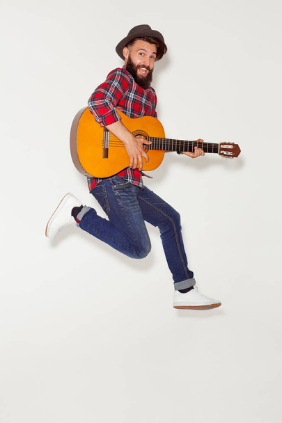 Energetic man jumping with guitar - Photo, Image