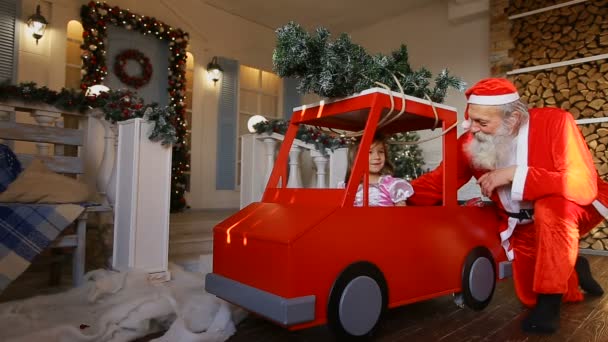 Ο πατέρας των Χριστουγέννων έδωσε θηλυκό παιδί μεγάλο παιχνίδι αυτοκίνητο στη βεράντα του σπιτιού, διακόσμηση για διακοπές - Πλάνα, βίντεο