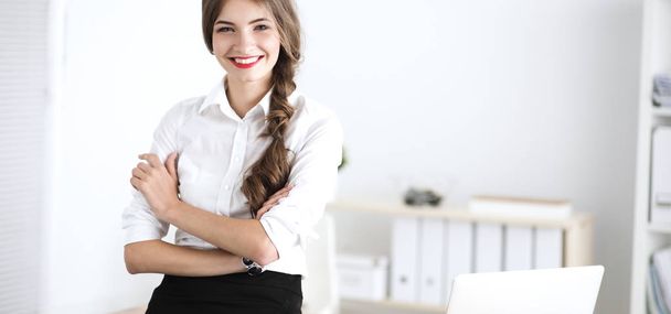 Attractive businesswoman with her arms crossed  standing in office - Foto, afbeelding
