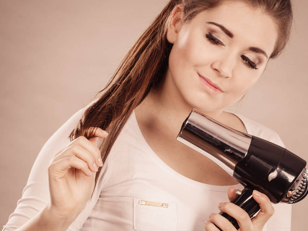 Woman drying her hair using hair dryer - Valokuva, kuva
