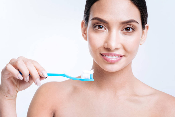 Smiling woman holding a toothbrush with some toothpaste on it - Photo, Image