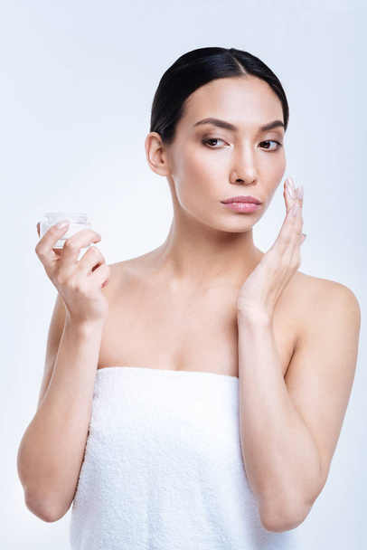 Pretty woman in towel applying face cream - Fotó, kép