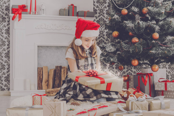 Belle fille dans santa chapeau déballage cadeaux de Noël
 - Photo, image
