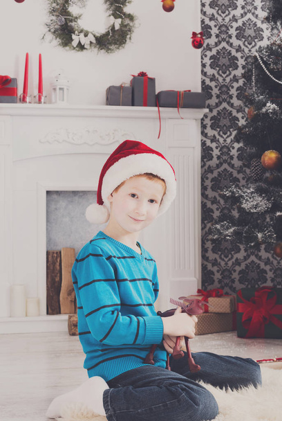 Cute happy boy in santa hat with toy christmas presents - Photo, Image
