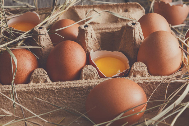 Uova fresche di pollo marrone in cartone su fondo di legno rustico
 - Foto, immagini