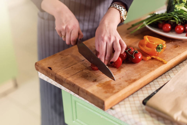 Close-up beeld van jonge vrouw s handen snijden groenten aan boord voor pizza volgens receptenboek - Foto, afbeelding