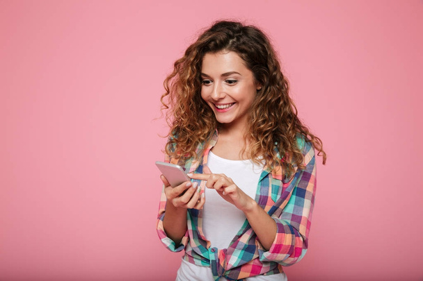 Cheerful woman using smartphone isolated over pink - Zdjęcie, obraz