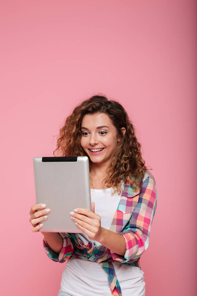 Young caucasian brunette lady using tablet computer isolated over pink - 写真・画像
