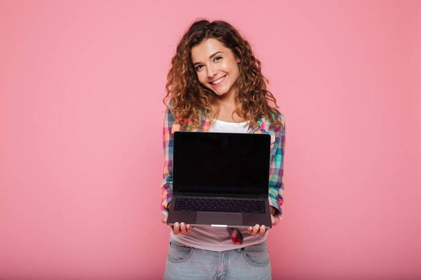 Jeune femme pointant vers l'espace de copie sur ordinateur portable isolé sur rose
 - Photo, image