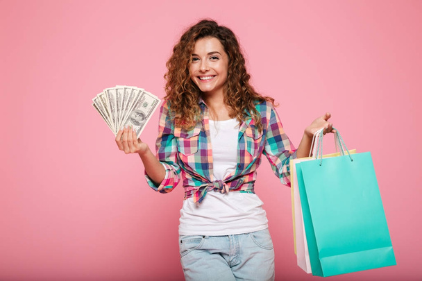 Happy woman with money and shopping bags posing isolated - Foto, immagini