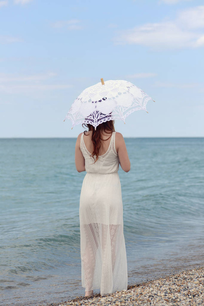 redhead woman with umbrella at the beach - Fotoğraf, Görsel