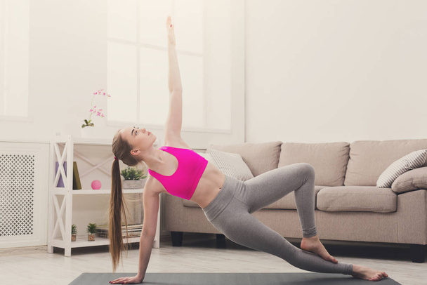 Mujer entrenando yoga en pose de tablón lateral
. - Foto, imagen