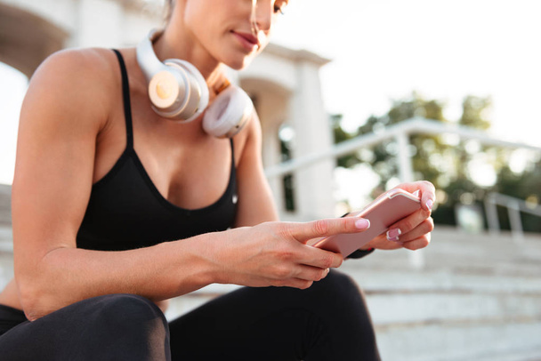 Cropped photo of strong young sports woman chatting by phone. - Foto, Imagen