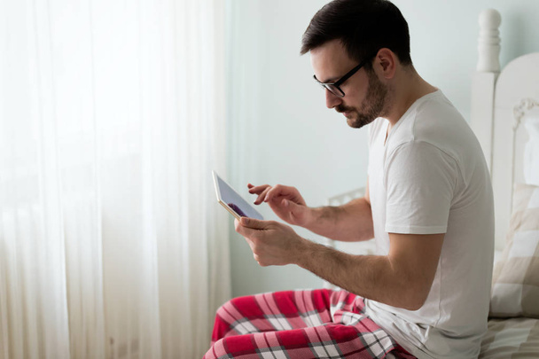 Mann mit digitalem Tablet im Bett - Foto, Bild
