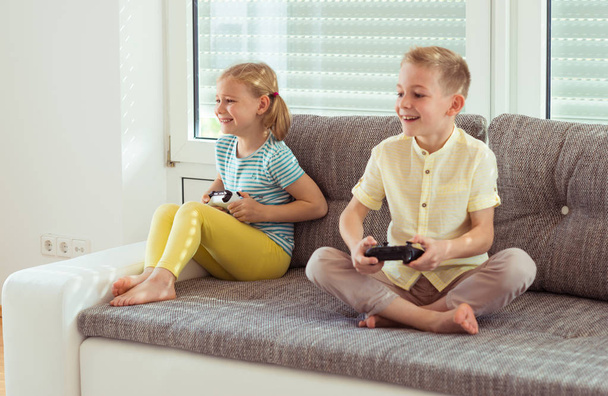 Two happy children playing video games at home - Foto, Imagen