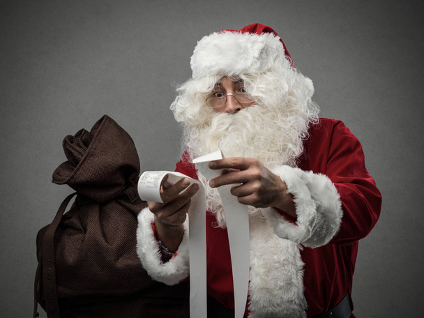 Santa Claus checking shopping bills - Foto, Imagen