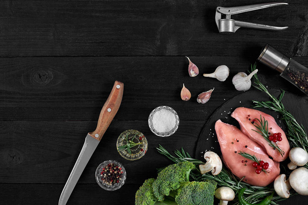 Chicken breast on a cutting board with herbs and different vegetables on rustic wooden background. - Fotoğraf, Görsel
