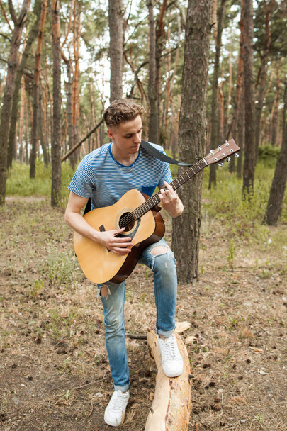 Pensive man playing guitar forest concept. - Fotoğraf, Görsel