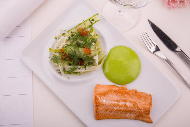 The smoked salmon fried on melted butter is served with salad and cream from leek - Foto, Imagem