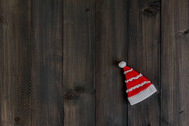 Sombrero de Santa Claus sobre fondo rústico oscuro de madera con espacio de copia para texto - Foto, Imagen