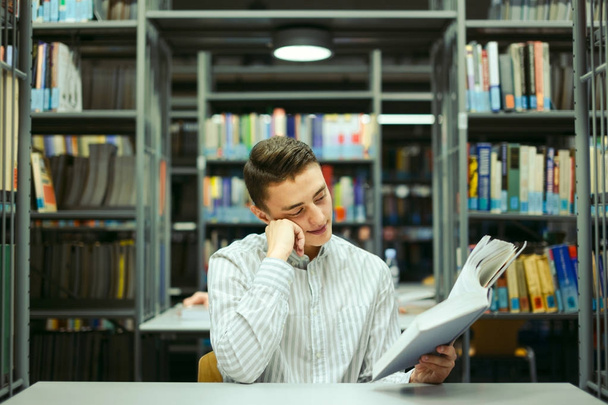 Человек сидит на библиотеке и читает книги с размытым фоном
 - Фото, изображение