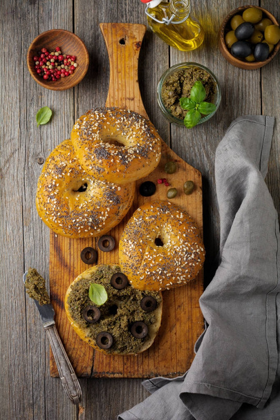 Tapenade, traditional Provence dish with black and green olives, basil and Bagels on old  wooden table background. - Fotografie, Obrázek