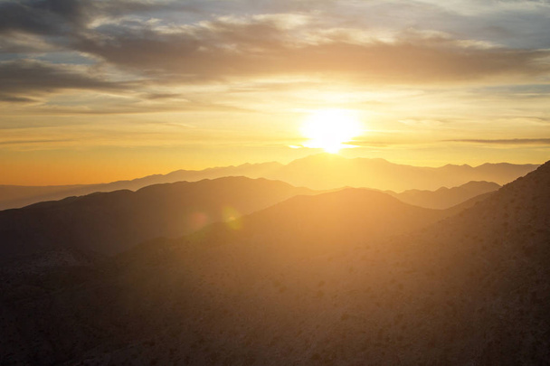 Brilhante vista do pôr do sol sobre a paisagem montanhosa do deserto
 - Foto, Imagem