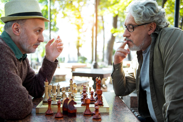 Mature male friends entertaining with chess game - Valokuva, kuva