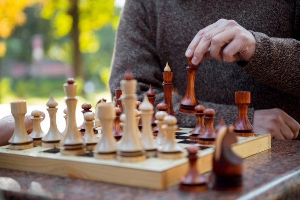 Senior male arm moving statuette on chessboard - Foto, afbeelding