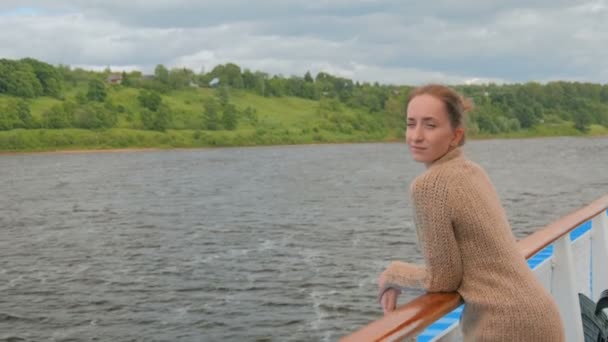 Молода жінка стоїть на палубі круїзного корабля і дивиться на річку і ландшафт
 - Кадри, відео