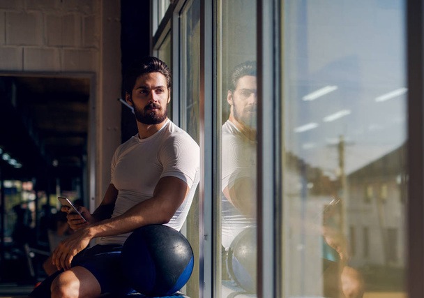 muscular man sitting near window - Valokuva, kuva