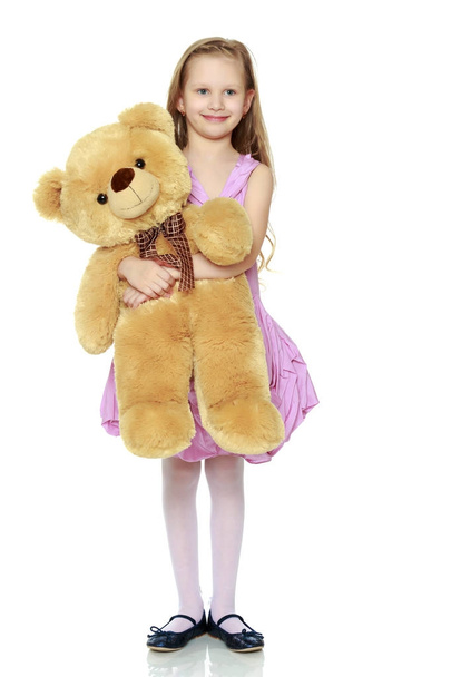 Beautiful little girl 5-6 years.She is holding a large teddy bea - Foto, afbeelding