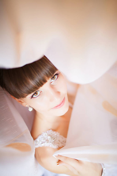 όμορφη νεαρή νύφη με γάμου μακιγιάζ και χτένισμα σε υπνοδωματίω - Φωτογραφία, εικόνα