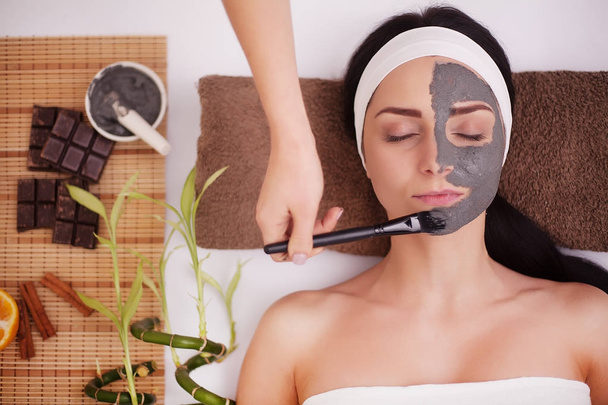 Appliquer un masque facial sur le visage de la femme au salon de beauté
 - Photo, image