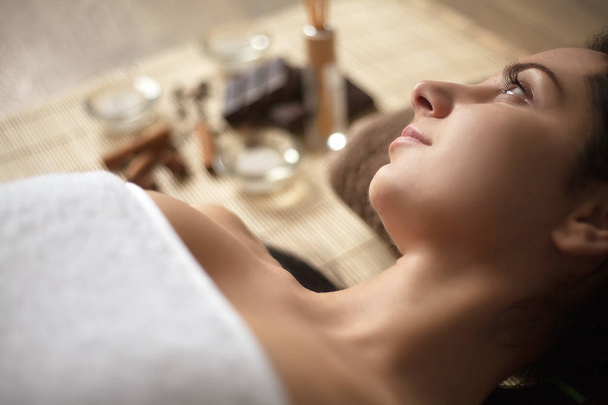Young woman lay on spa bed with spa ingredients and materials - Photo, Image