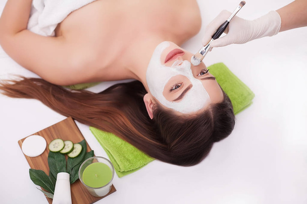Женщина-спа надевает маску для очищения лица. Косметические процедуры. Маска Клэя
 - Фото, изображение