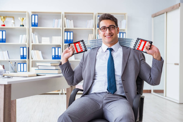Молодой бизнесмен с эластичным расширителем в офисе - Фото, изображение