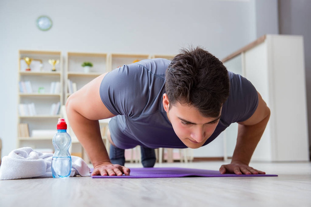 Young man exercising at home in sports and healthy lifestyle con - Photo, Image