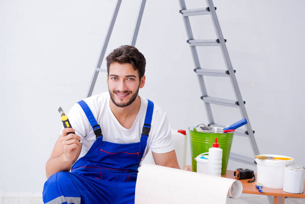 Naprawiający wykonuje remonty w domu z papierową tapetą - Zdjęcie, obraz