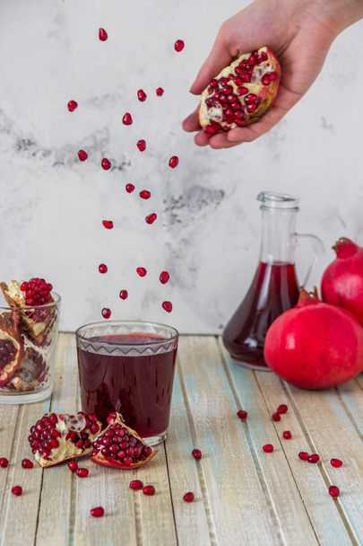 pomegranate juice and fruit slices. Grains are flying over the g - Photo, Image